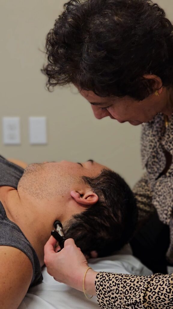 Dr. Parto using the Activator on a patient's neck